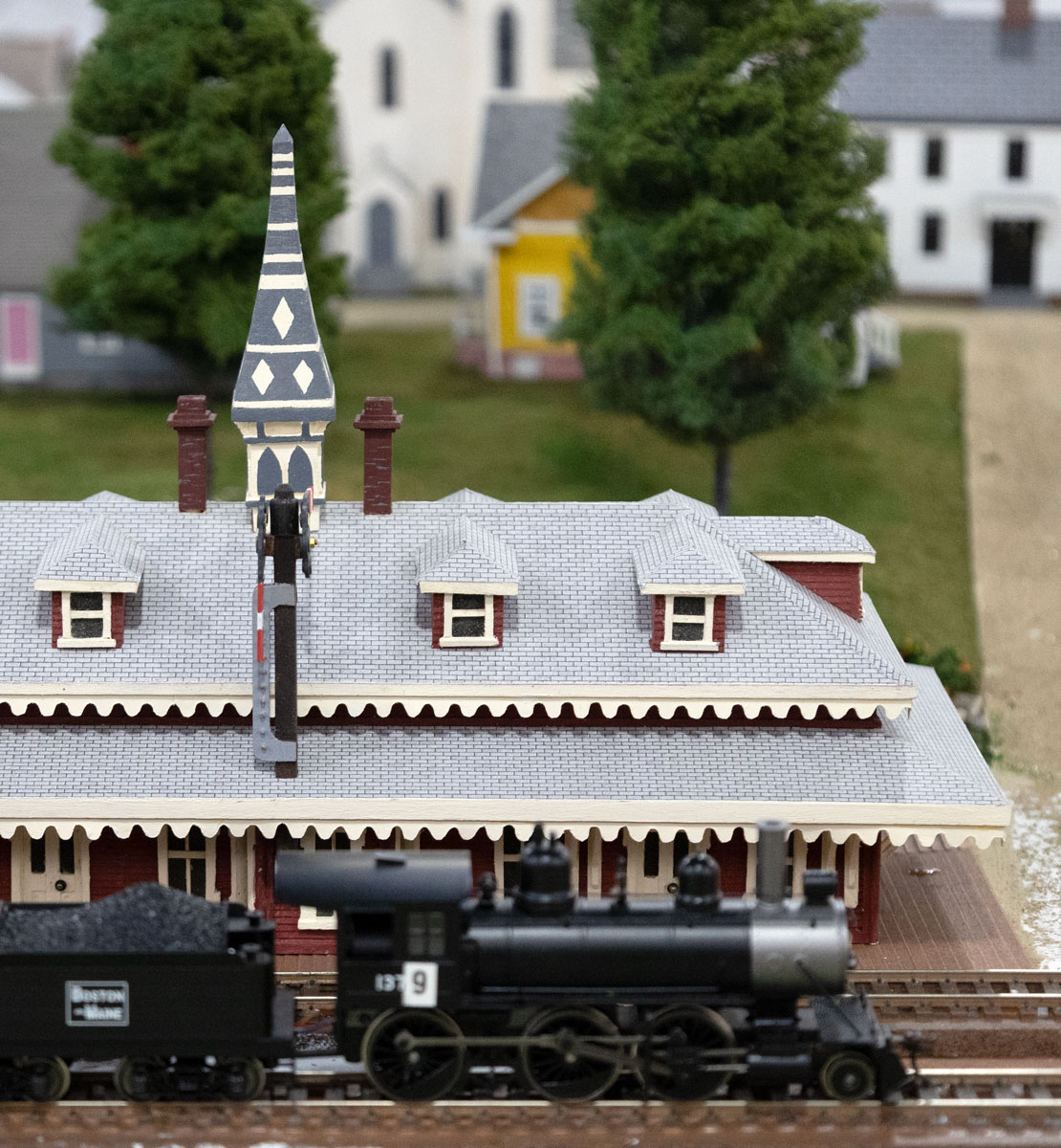 Model steam locomotive and Boston & Maine tender at a station on the layout